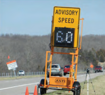 A Portable Variable Speed Limit on wheels along the side of the road displaying an Advisory Speed of 60 mph. 