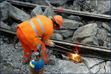 A person wearing an orange safety vest performing predictive railroad maintenance. 