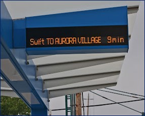Real Time Arrival Board saying "Swift to Aurora Village 9 minutes" at a transit stop in Washington State.