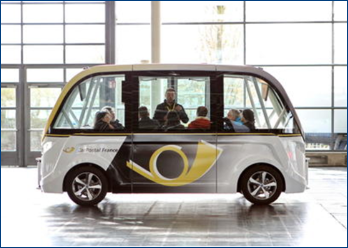 NAVYA SAS autonomous shuttle on display at a convention with attendees sitting onboard. 