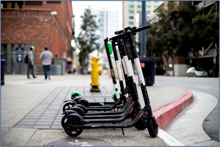 E-scooters lined up along a sidewalk.