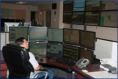 A Transportation Management Center (TMC) employee sitting at a desk in front of multiple screens monitoring highway activity.