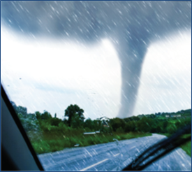 A vehicle driving along a road in rainy  conditions toward a tornado funnel.