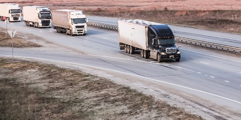 Line of trucks "platooning" down a divided highway.