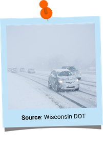 Photo of a car driving in a snowstorm on a road