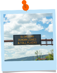 Message sign over road displaying "Slow down in work zones and toll plazas""