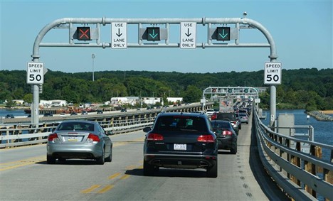 image of cars on a roadway going under an overhead series of electronic signs showing what lanes are open and closed