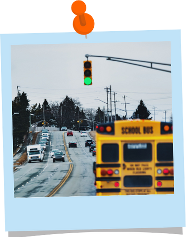 A school bus driving on a four lane road through a green light.