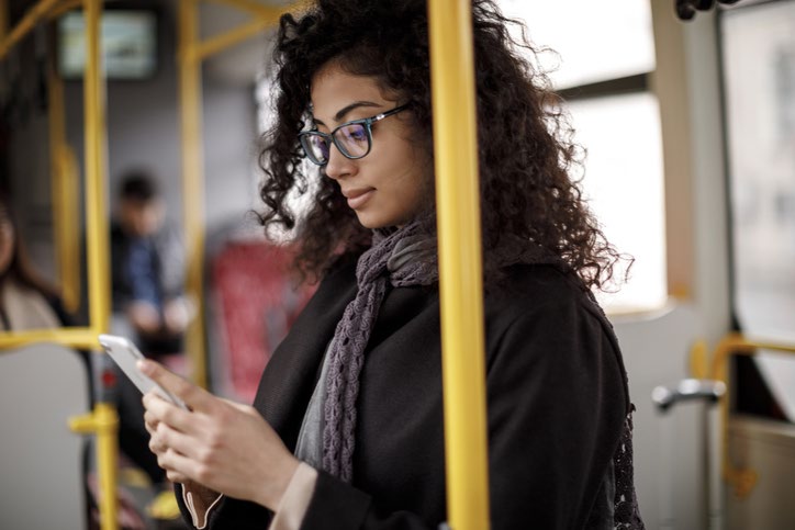 A woman using a phone while sitting on a bus. 