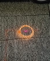 A chalk circle drawn on pavement with a laser dot in the center. 