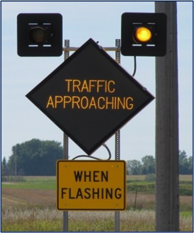 A flashing sign on the side of a road that reads 'traffic approaching when flashing.'